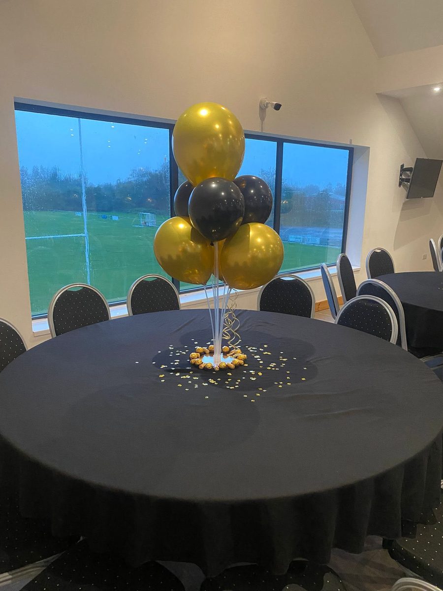 Close-up of a gold and black balloon centrepiece on one of the function room's tables